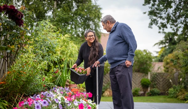 Woman Holding A Plant Pot In The Garden With Older Man