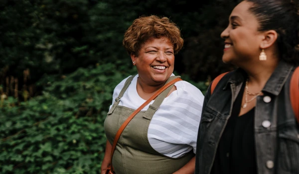 Two Smiling Women Walking Together In Woods (1)