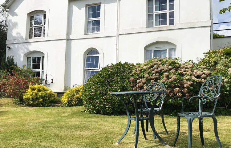 View of the garden with table and chairs on lawn at Abbeyfield House, St Austell