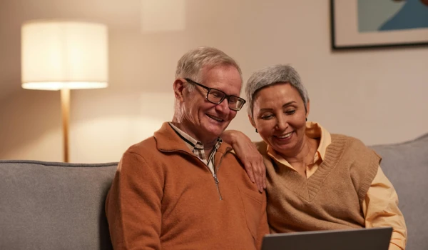 Smiling Older Couple Looking At Laptop Together On The Sofa